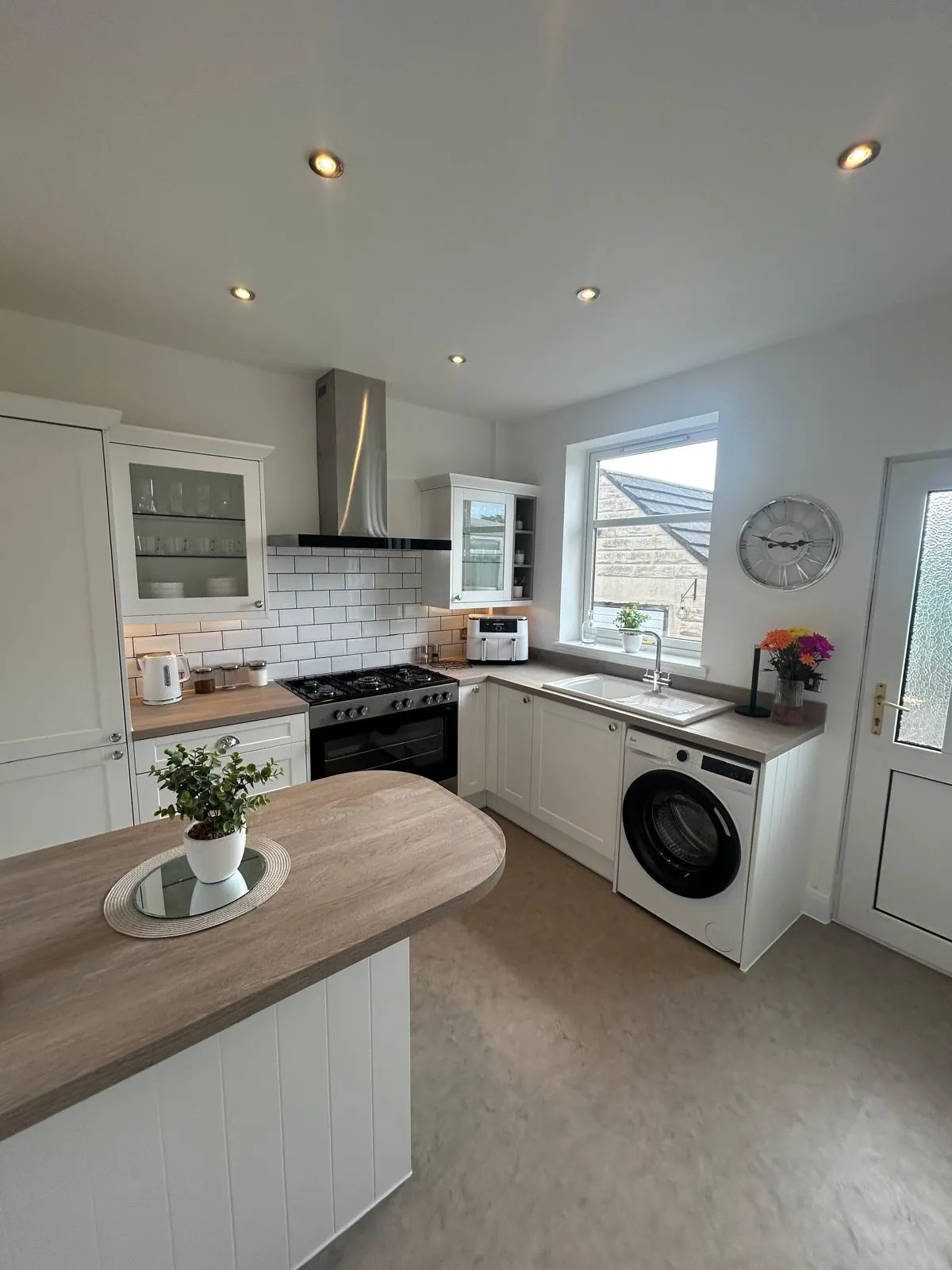 White fitted kitchen with wood-effect worktops and a small peninsula